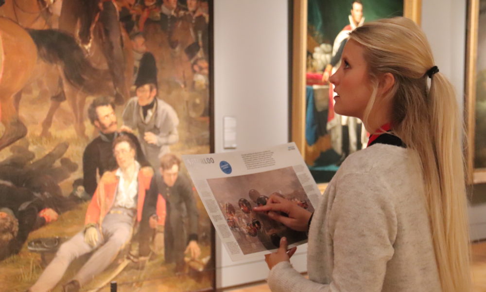 Tourist looking at paintings in Amsterdam. She is studying the artwork carefully.