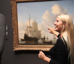 Woman pointing at a painting. A man looking at art.