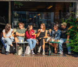 Group of friends chatting outside a cafe. Young people enjoying a sunny day in Amsterdam.