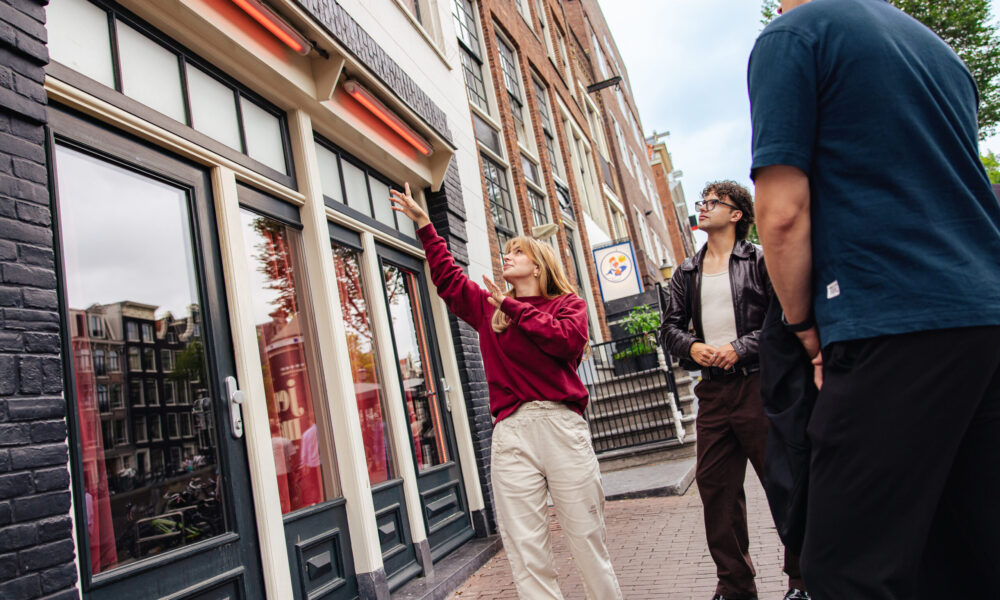 People on a street in Amsterdam. A woman pointing at a building.