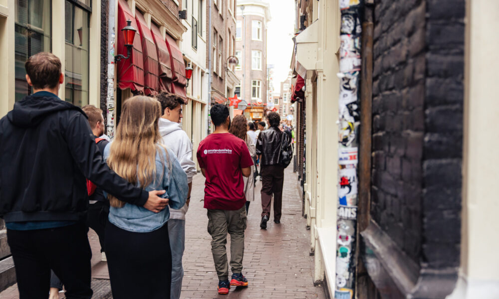 Group of tourists walking down a charming narrow street. Colourful buildings line the cobblestone alleyway.