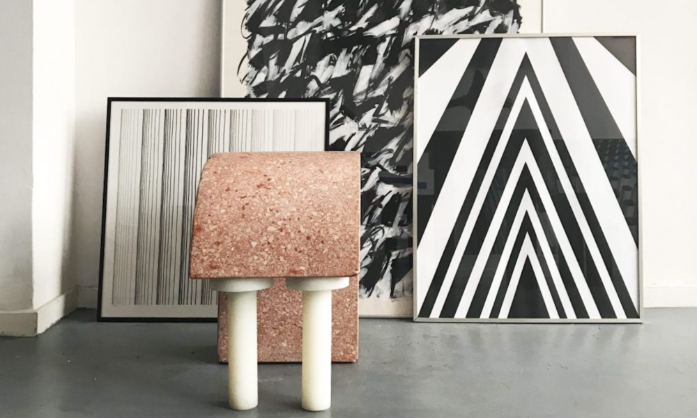 Modern art pieces on display in a room. A pink stone table with white legs.