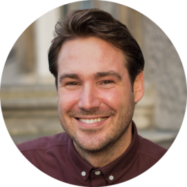 A smiling man with short brown hair wearing a maroon shirt. He appears friendly and approachable.