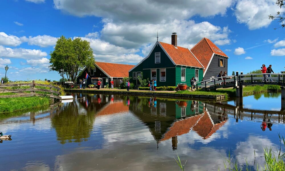 Traditional Dutch houses with orange roofs. A serene pond reflecting the houses.
