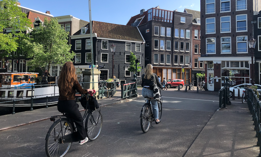 Due donne in bicicletta su un ponte ad Amsterdam