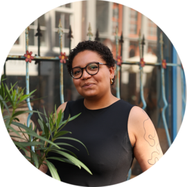 A woman with dark hair and glasses in Amsterdam. She is smiling and looking at the camera.