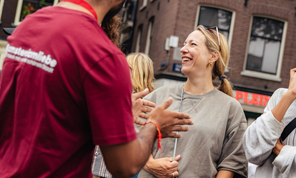 Tour guide in red shirt talking to smiling tourists